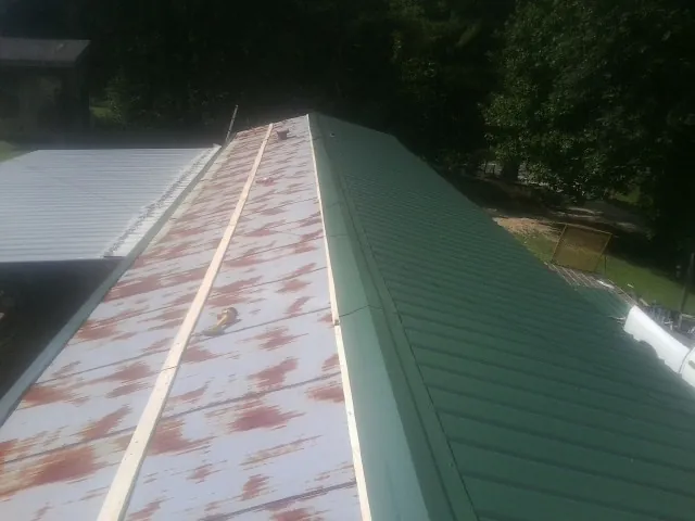 Old rusted panels beside newly installed green metal roofing — Wind Damage Roof Repair by Roofing Brothers in Fort Thomas