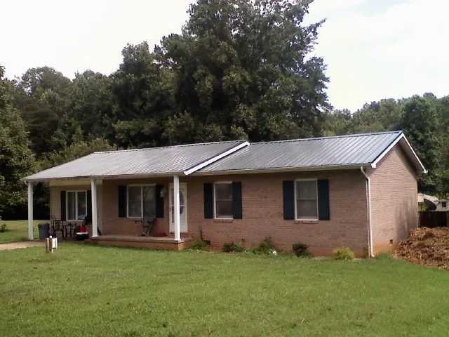 Gray metal roof on a brick ranch house with a side carport in Fort Thomas