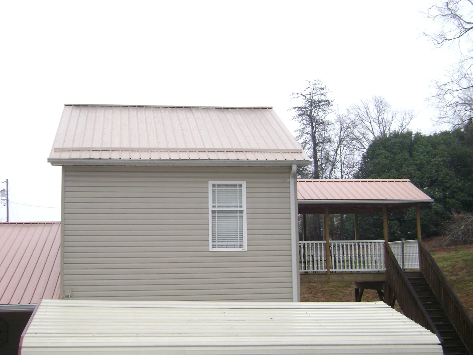 Tan metal roofs on a two story addition and attached porch, from a Roof Replacement job in Fort Thomas