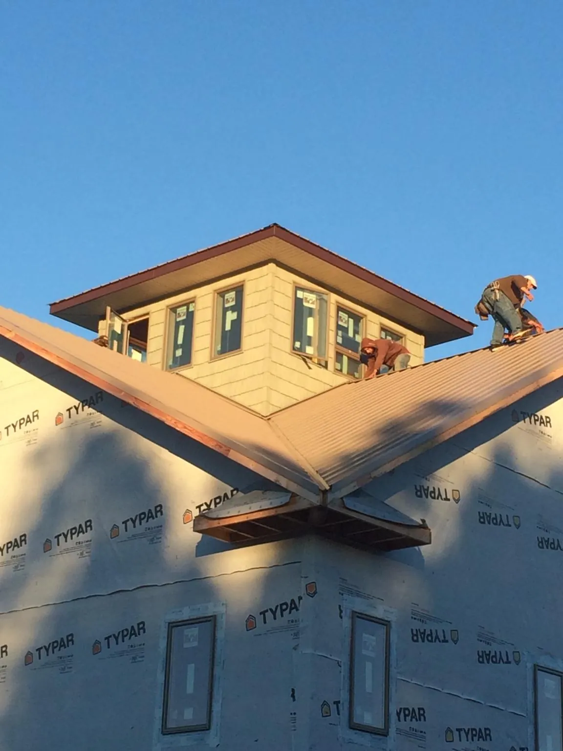 Roofers working around a rooftop cupola on a new metal roof at sunset — Roof Waterproofing in Fort Thomas by Roofing Brothers